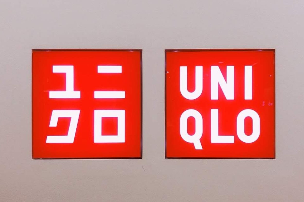 Two red signs with white text show the Uniqlo logo in Japanese and English