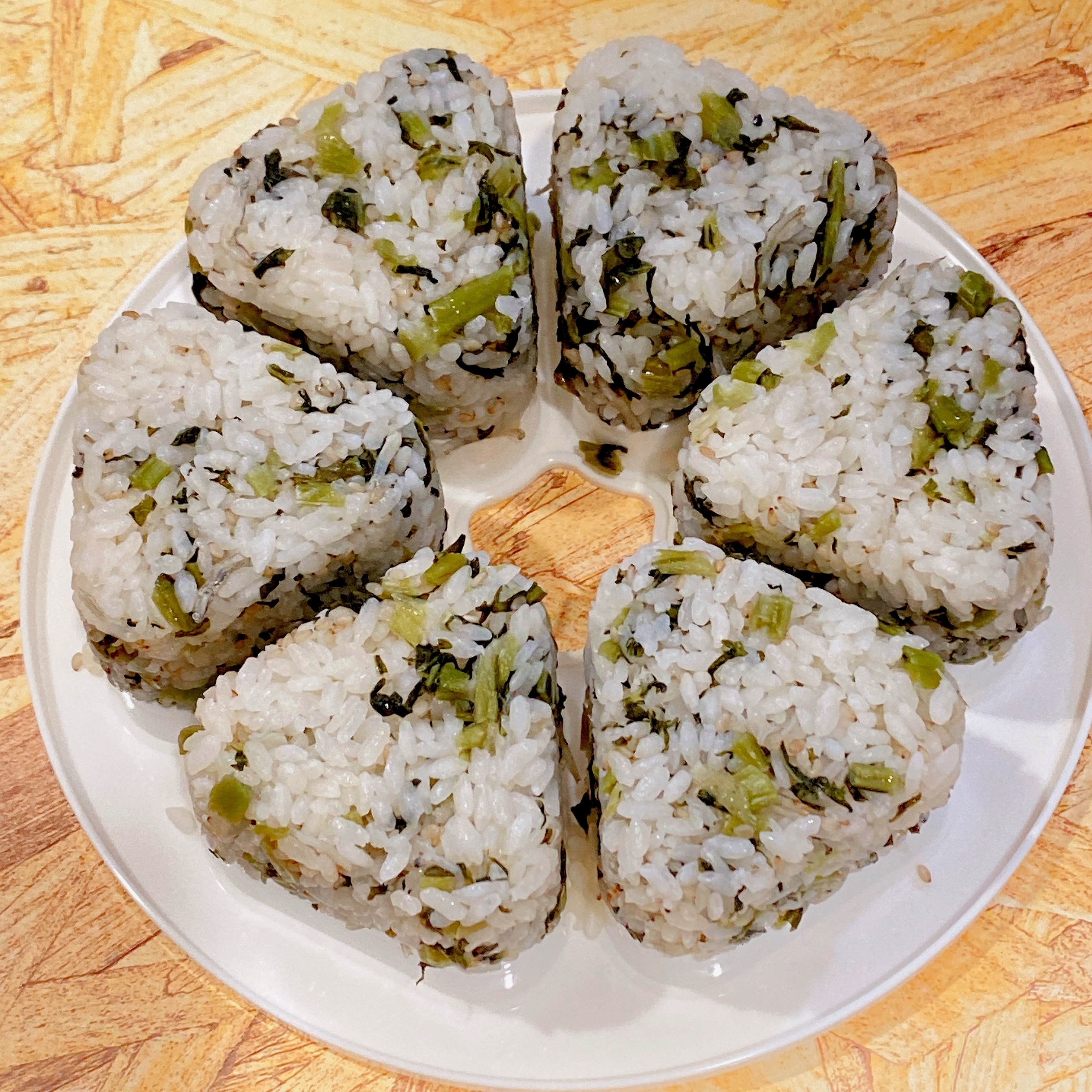 白皿に盛られた6個の三角おにぎり。海苔と青菜が混ざっている。