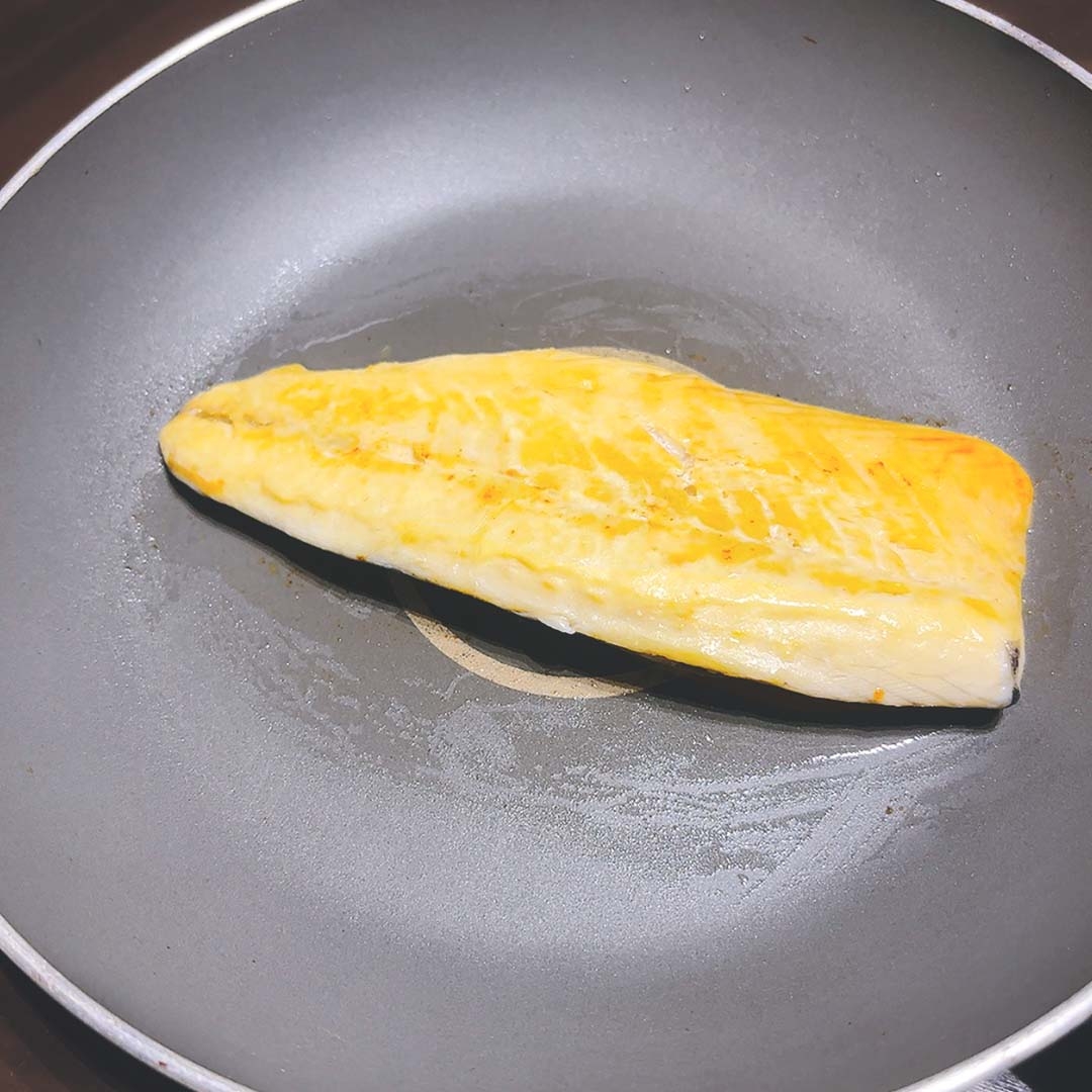 フライパンで調理中の魚の切り身。