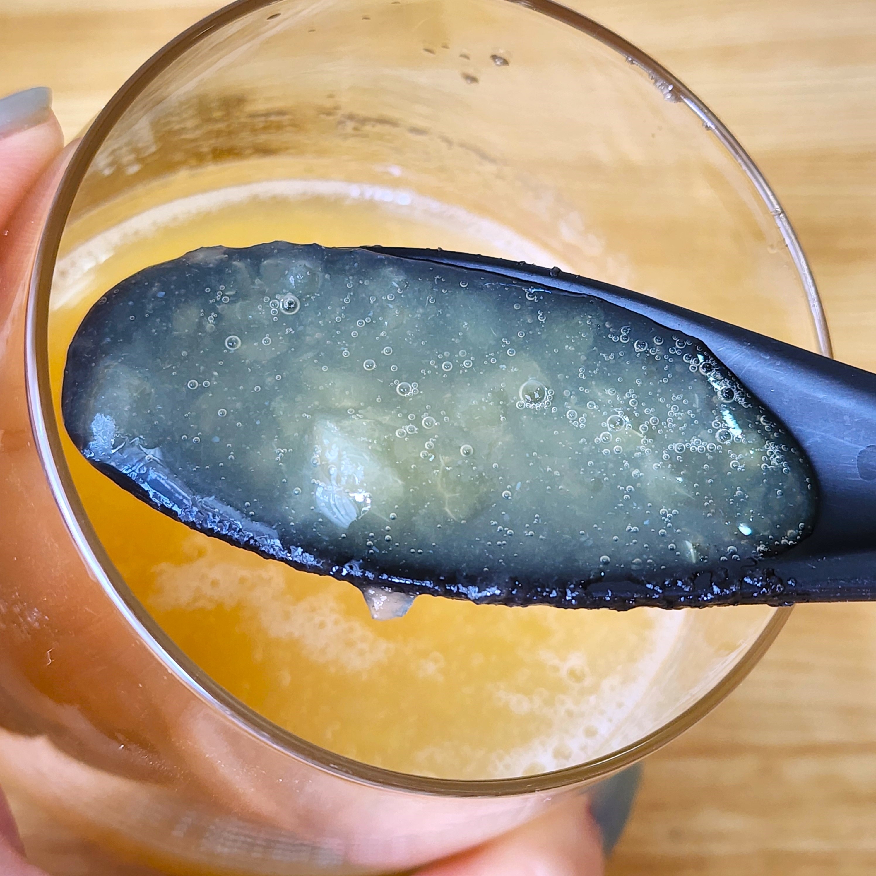 スプーン1杯のゼリー状の物質を飲み物に入れている様子。