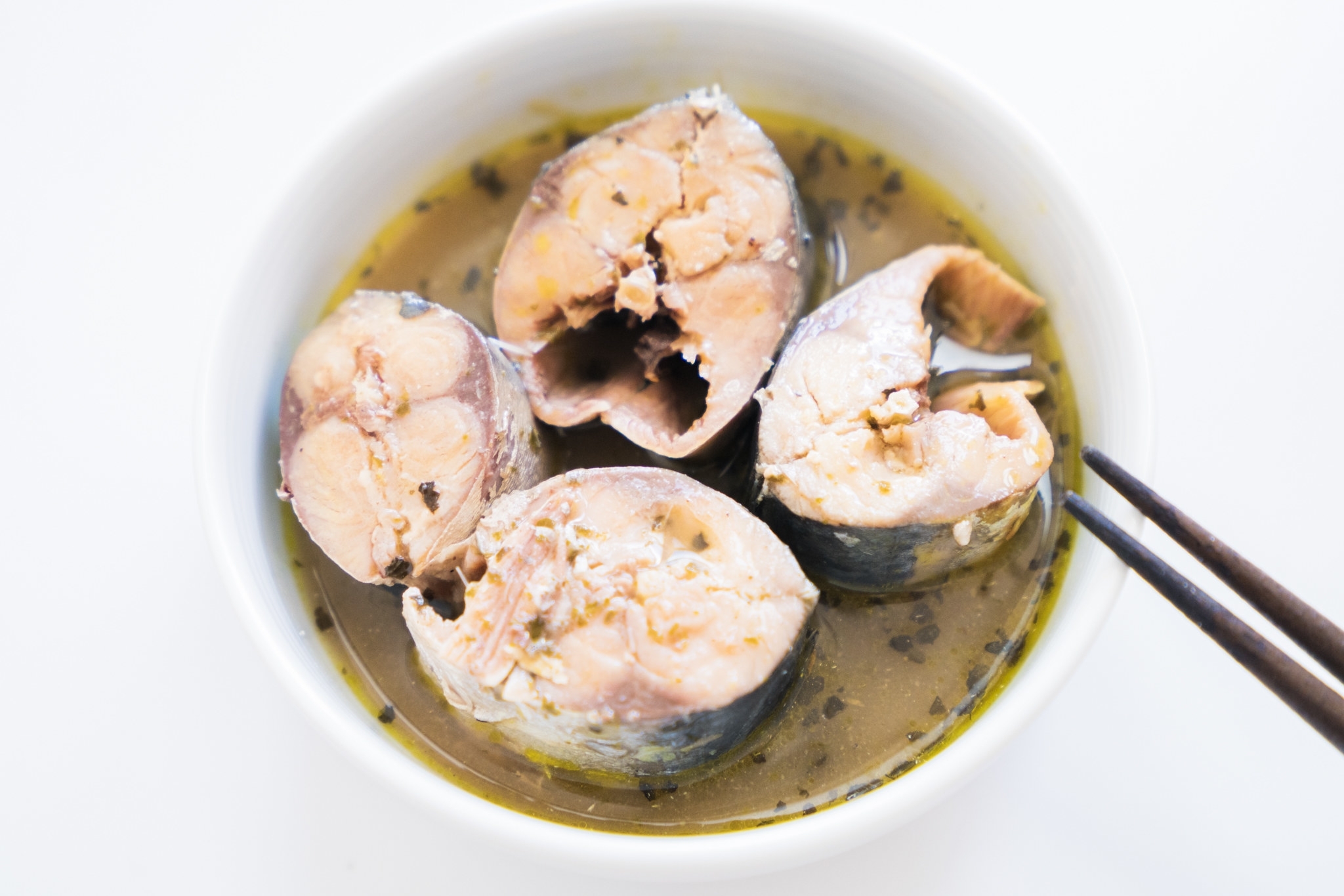 食器に盛られた魚の切り身がスープに浮かんでいる。箸が添えられている。