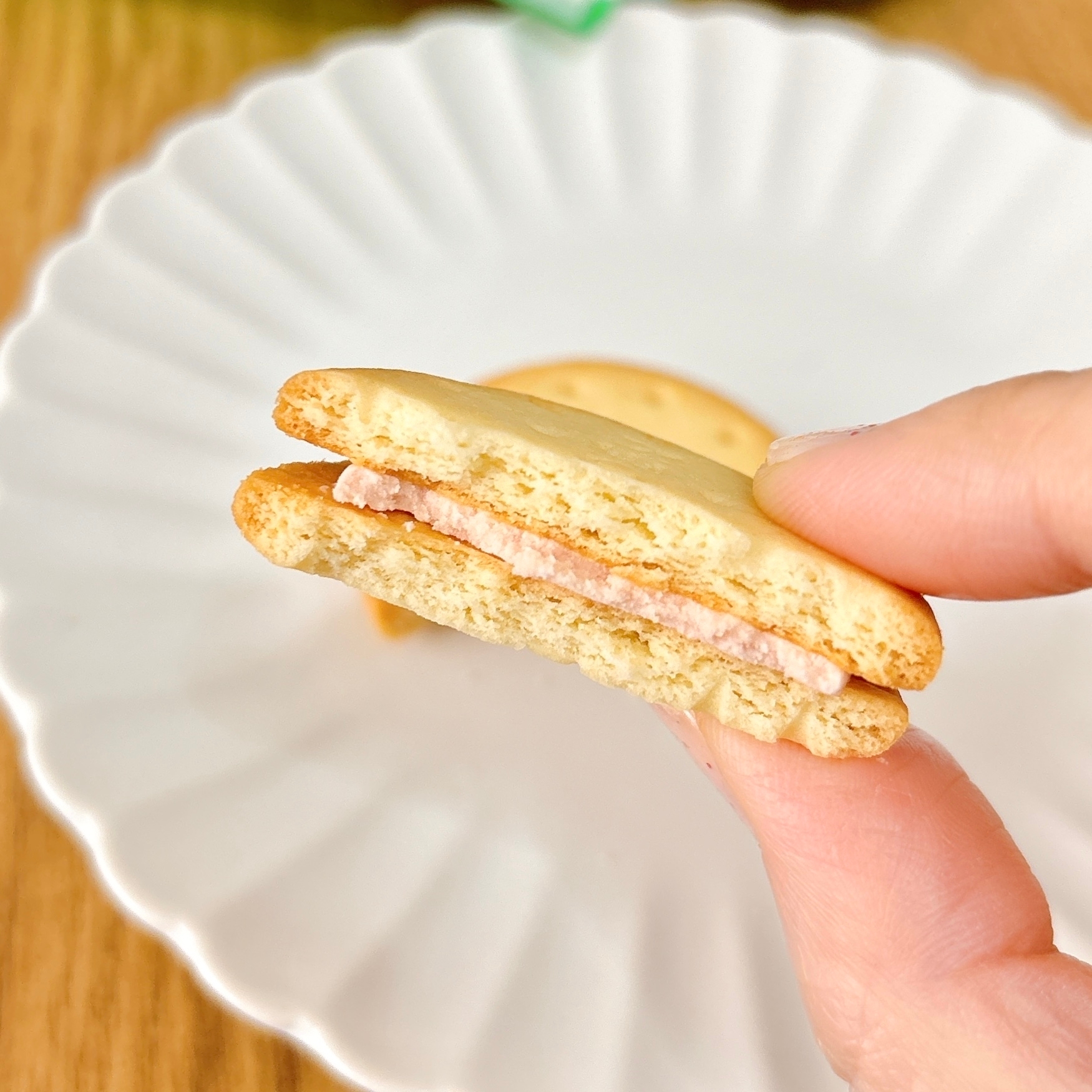 皿の上に置かれたクッキーを手で割った様子。間にクリームが挟まれている。