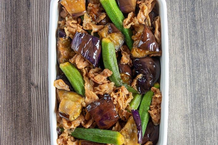 なすとズッキーニ、豚こま肉がミックスされた料理が白い容器に盛られている。