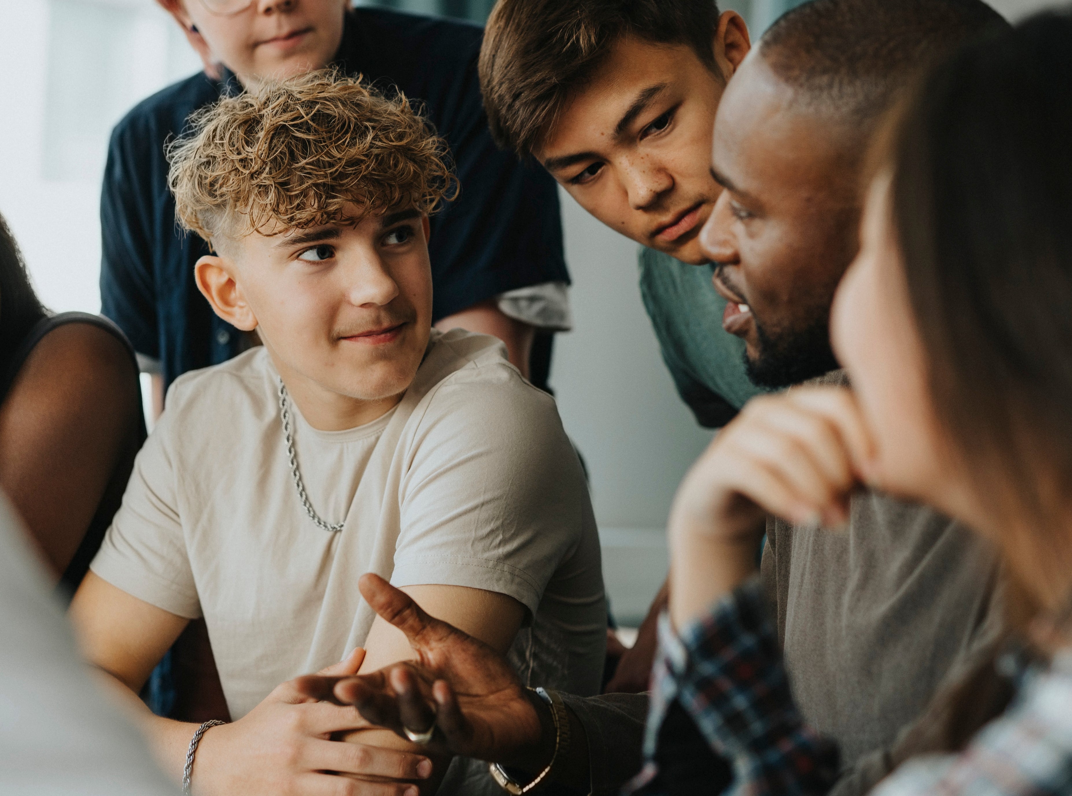 A group of diverse young adults engaged in a lively discussion, leaning in and listening attentively to one another