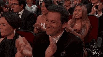 Audience applauds enthusiastically during an award show, with people clapping and smiling
