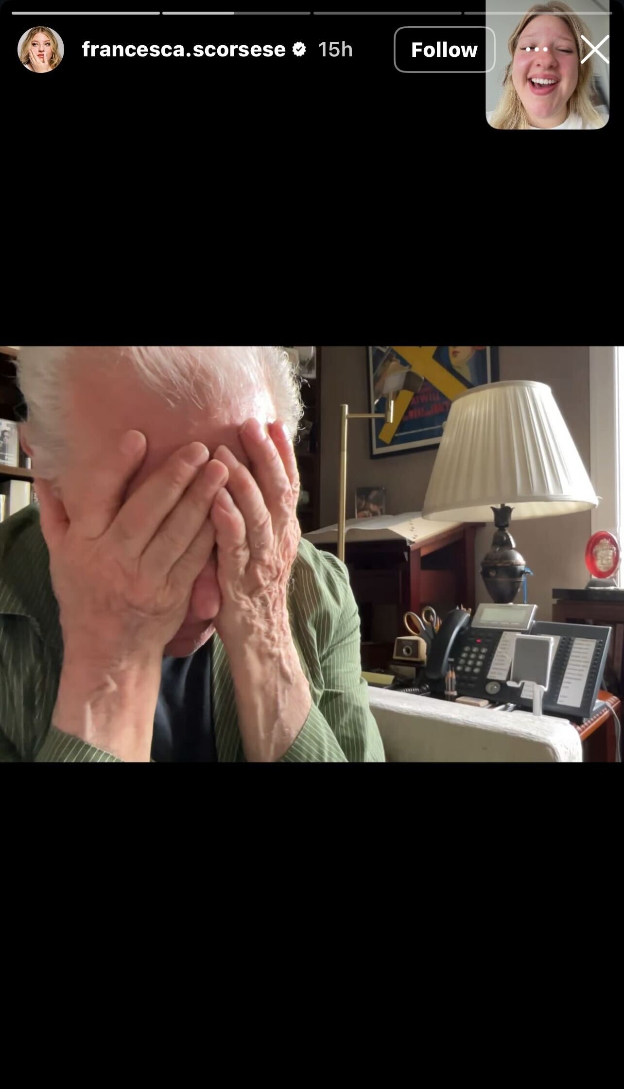 Person holding their face in their hands while seated at a desk in a home office setting. A small inset shows a smiling person in a video call