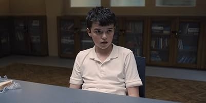 Teen sitting at a table, looking surprised or concerned, in a room with bookshelves in the background