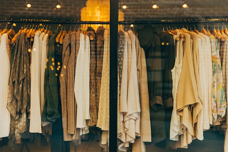 Clothing store window display with assorted tops and sweaters on hangers