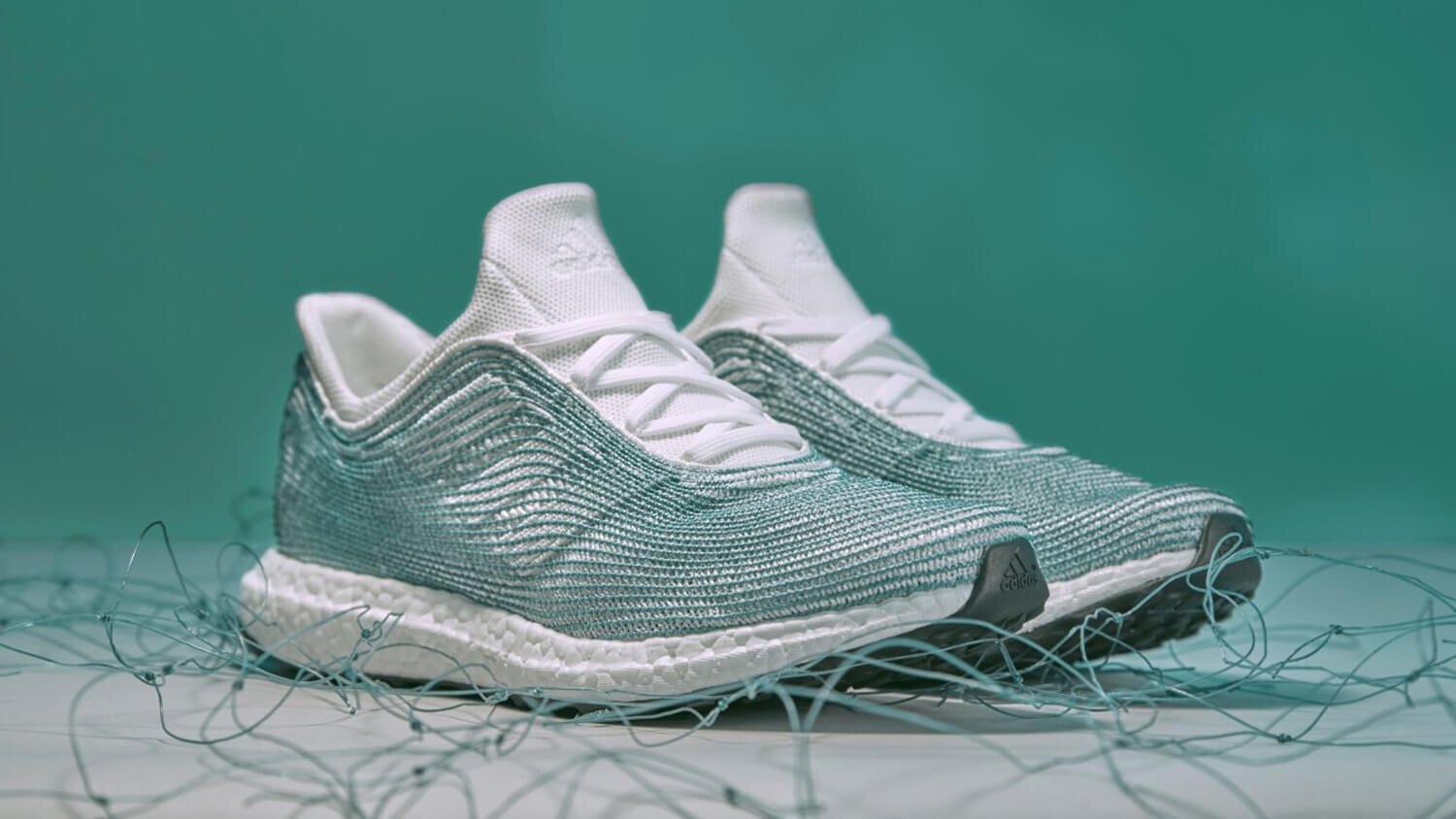 Pair of sleek, modern running shoes with knit texture and thick soles, surrounded by strands of yarn