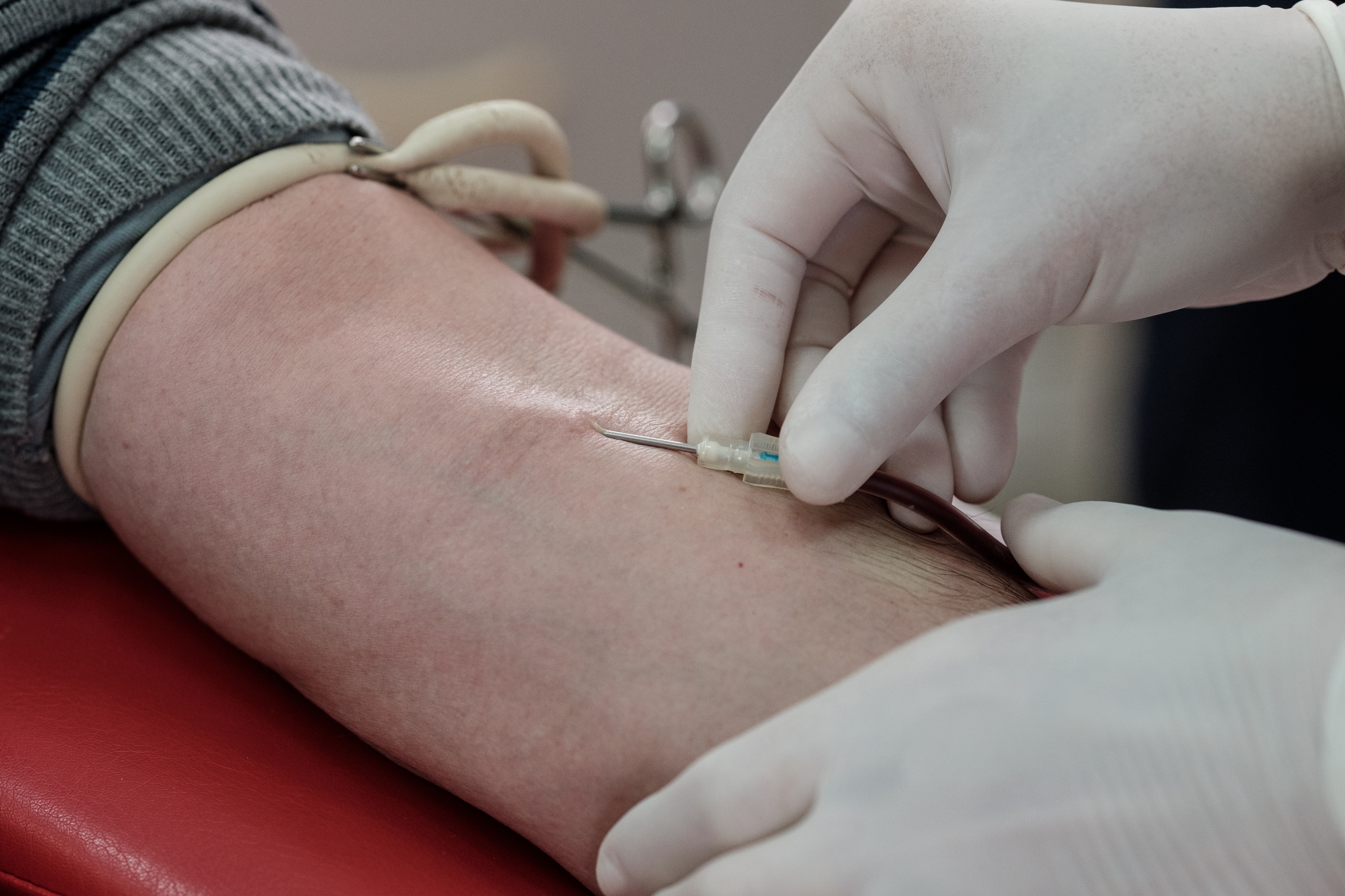 En hansk helsepersonell setter inn en nål i en persons arm for en blodtrekk