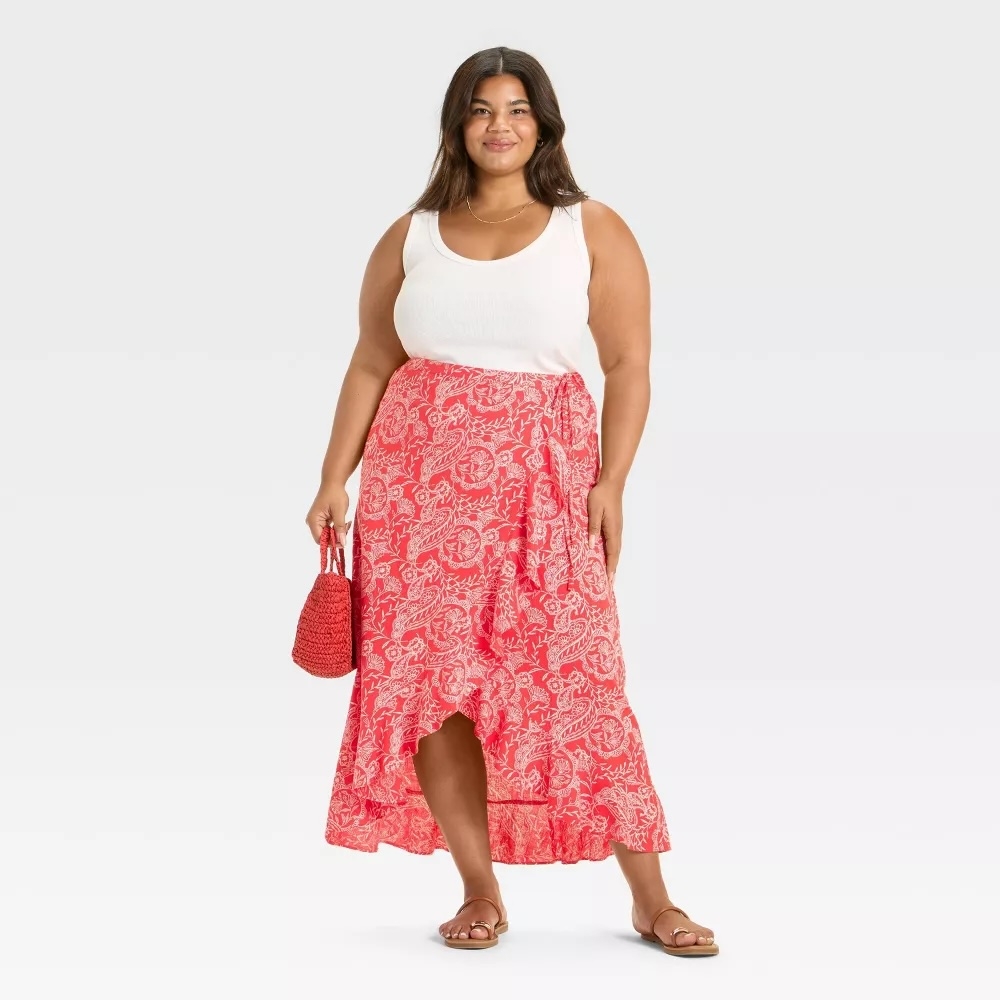 Model in a sleeveless top with a floral skirt, holding a matching handbag and wearing sandals, ideal for a casual summer look