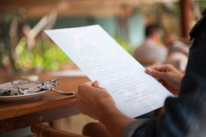 Orang membaca menu di meja restoran, siap memesan