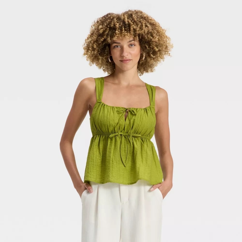 Model wearing a green top with white pants