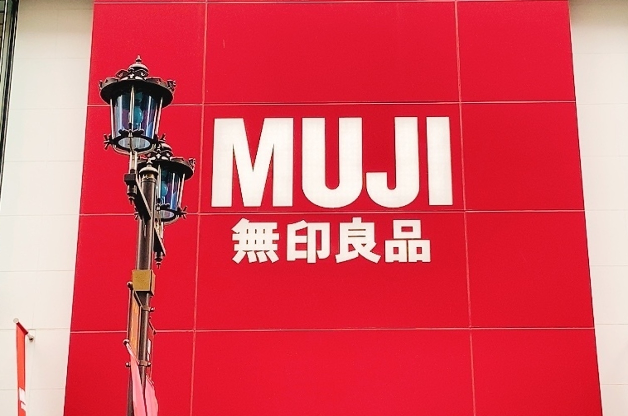 店の外壁に大きく「MUJI 無印良品」と表示されている看板。ランプポストが隣に立っている。