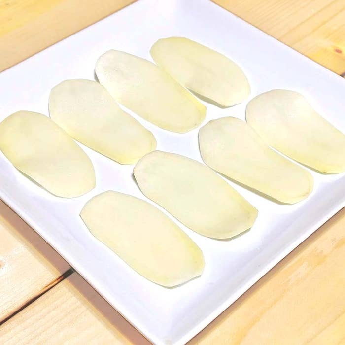 白い角皿に薄く切られたじゃがいものスライスが均等に並べられている。
