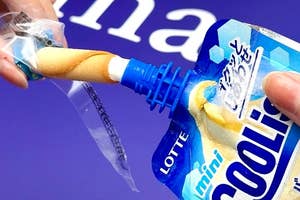 手にクリーム入りのパッケージを持ち、バニラ味のスナックを絞り出している様子。背景に文字が見える。