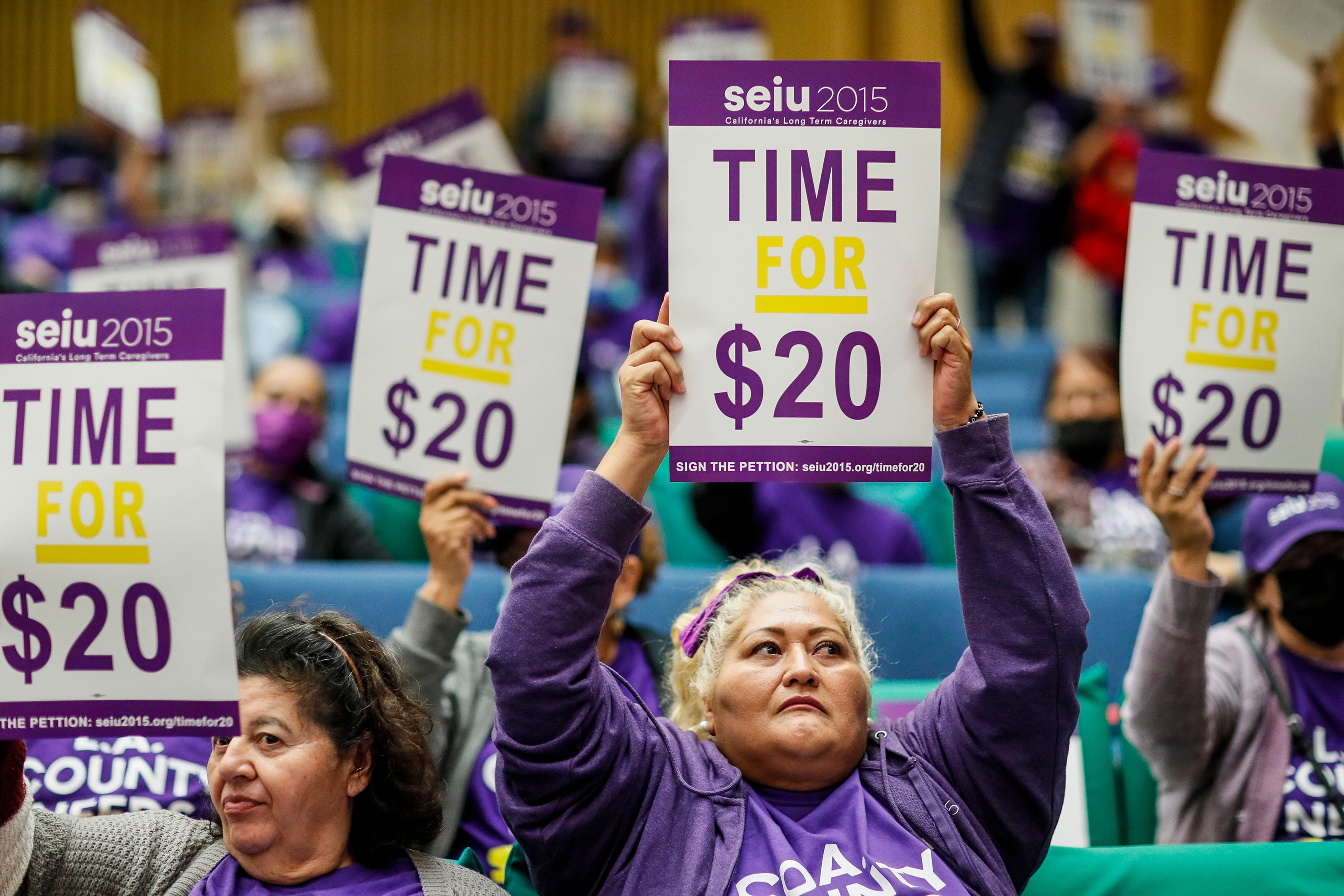 People hold signs reading &quot;Time for $20&quot; at a wage rally. Participants are wearing SEIU 2015 shirts and appear engaged in the event