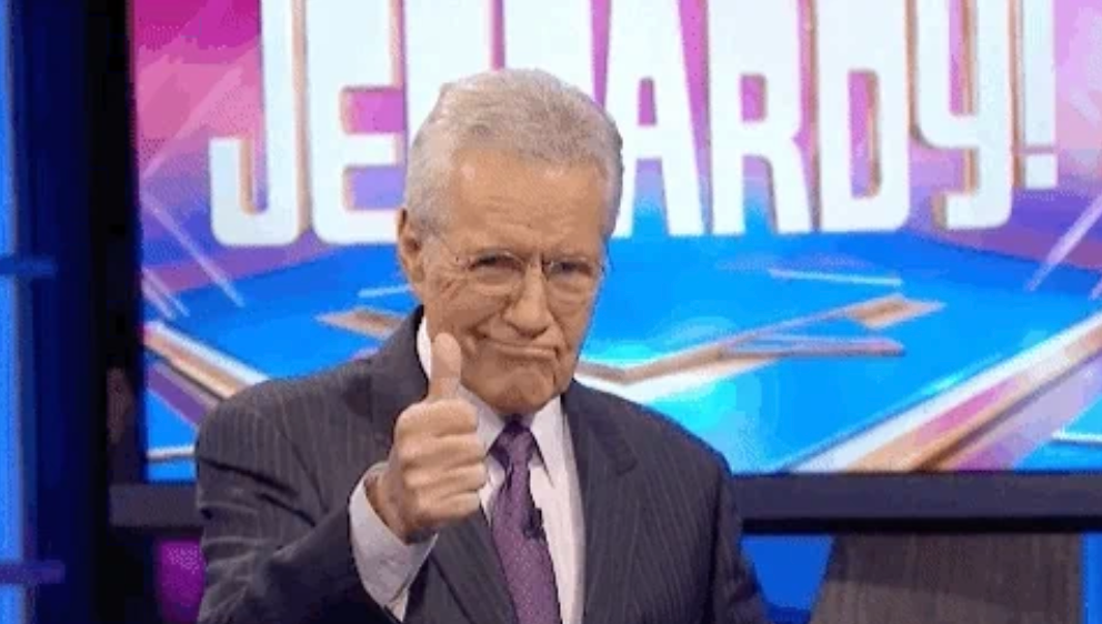 A man in a suit gives a thumbs-up on a game show set