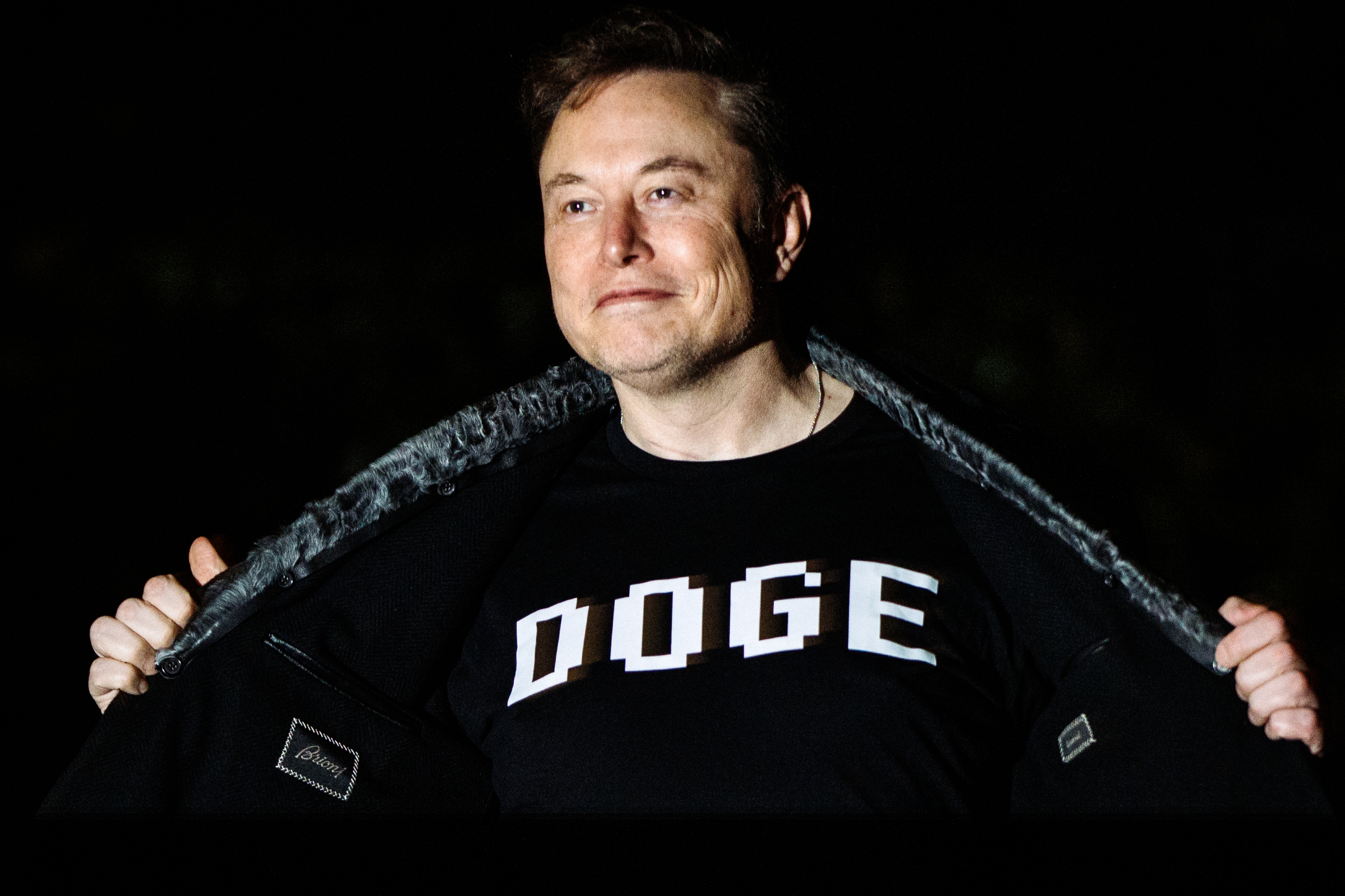 Person opening jacket to reveal a shirt with &quot;DOGE&quot; printed on it, with a confident expression