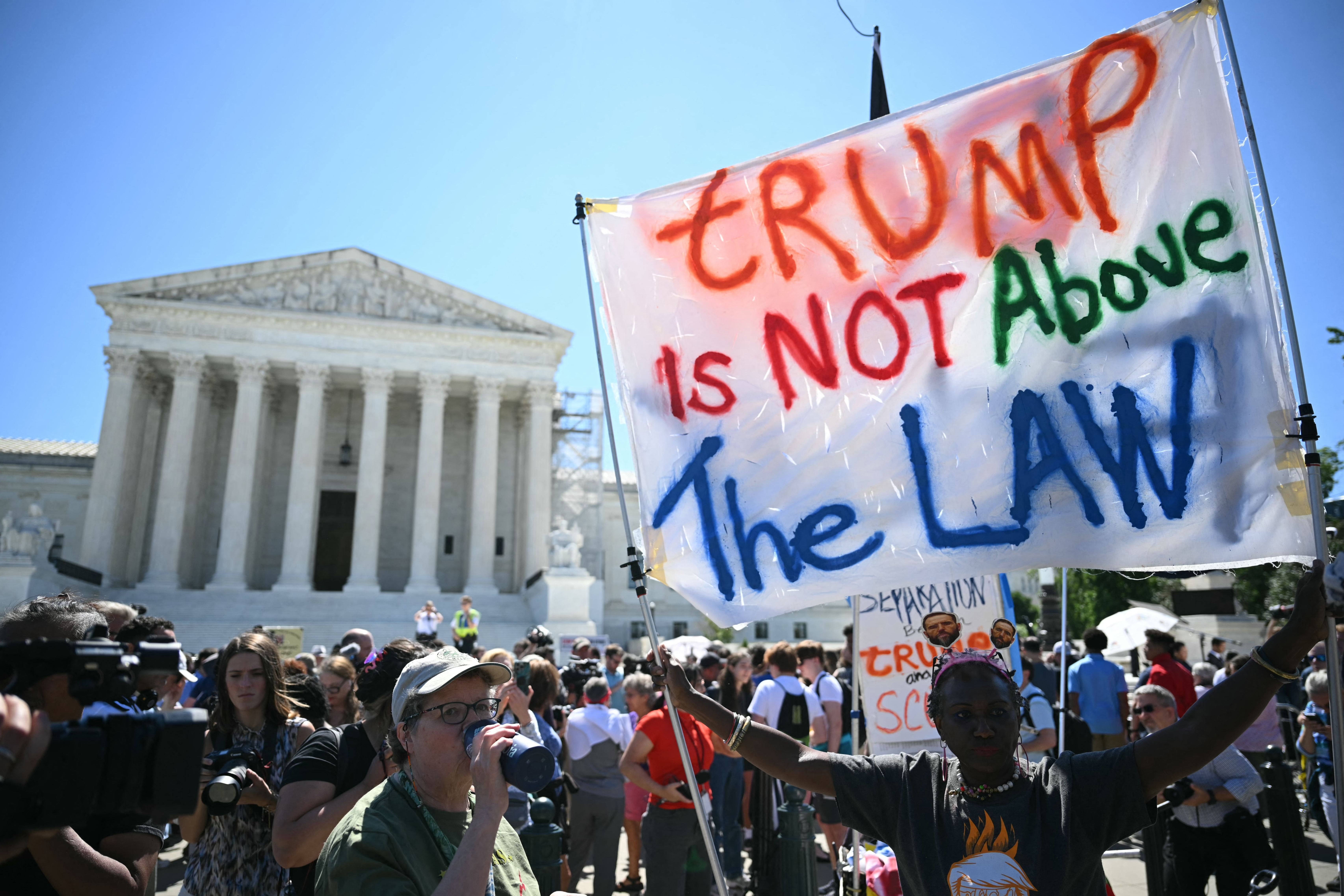 Protesters outside a government building hold a banner reading &quot;Trump is NOT Above the LAW&quot; during a public demonstration