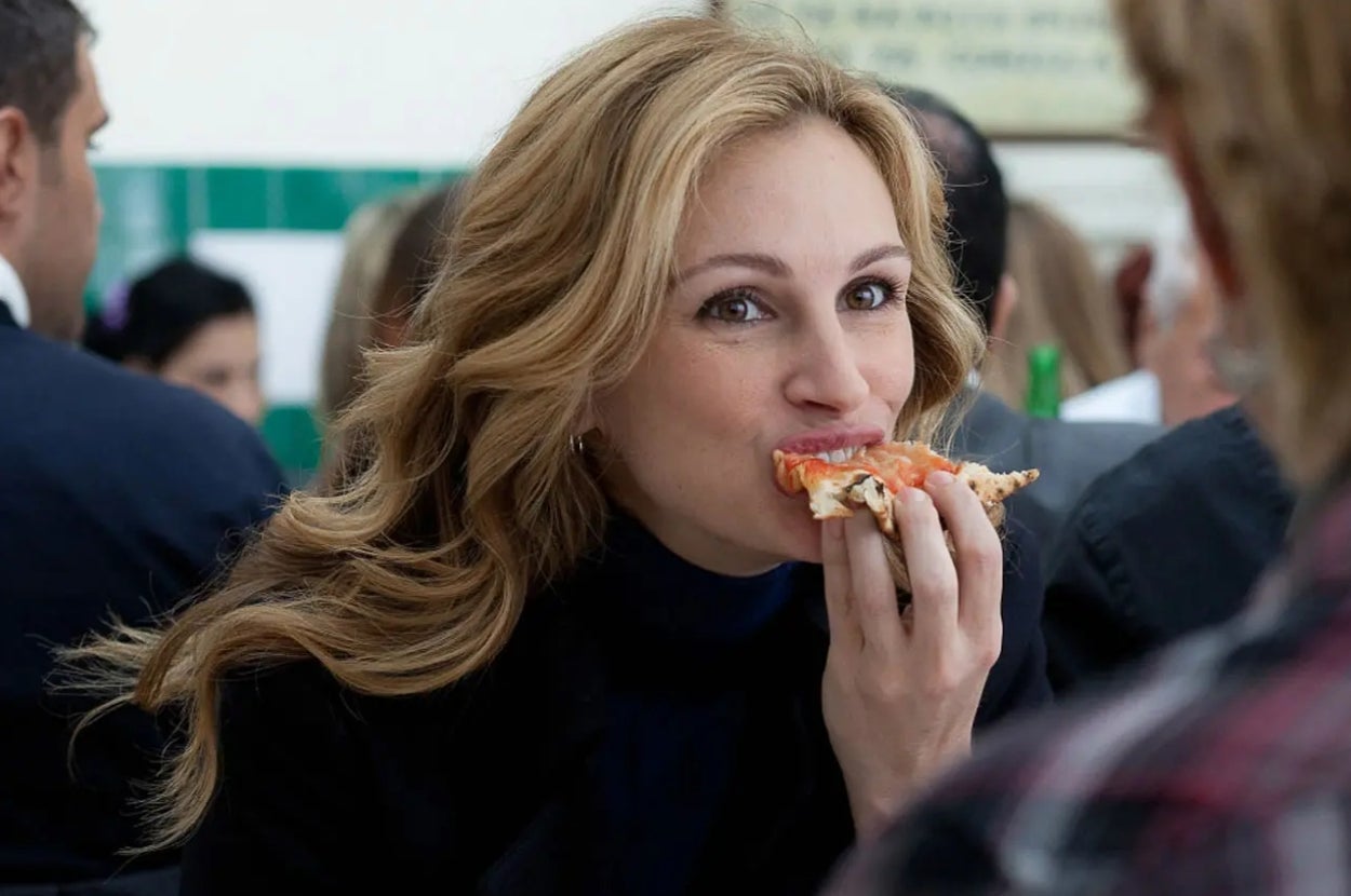 Person enjoying a slice of pizza at a gathering