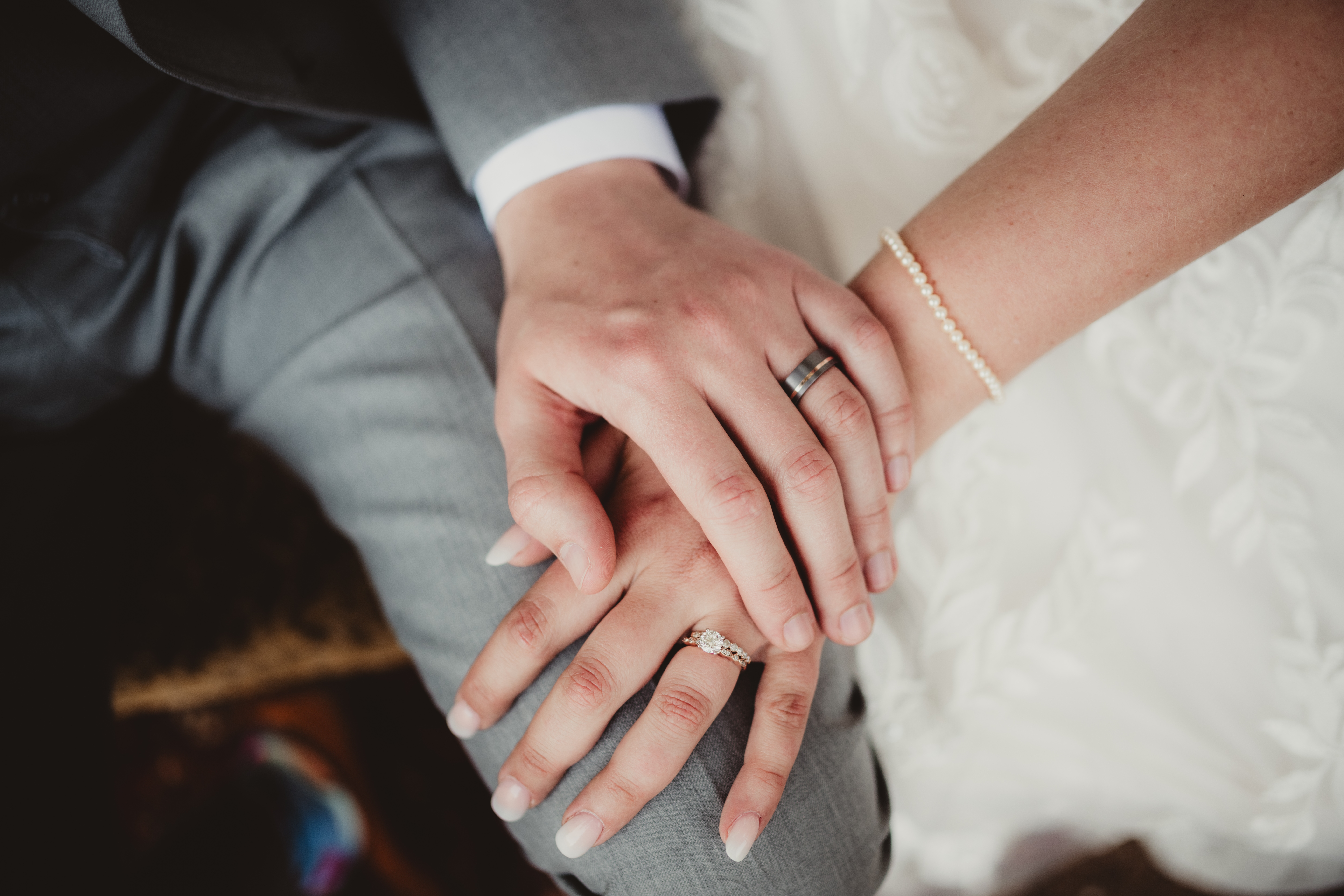 Et par sammenflettede hender, viser gifteringer og et armbånd, som symboliserer en kjærlig union