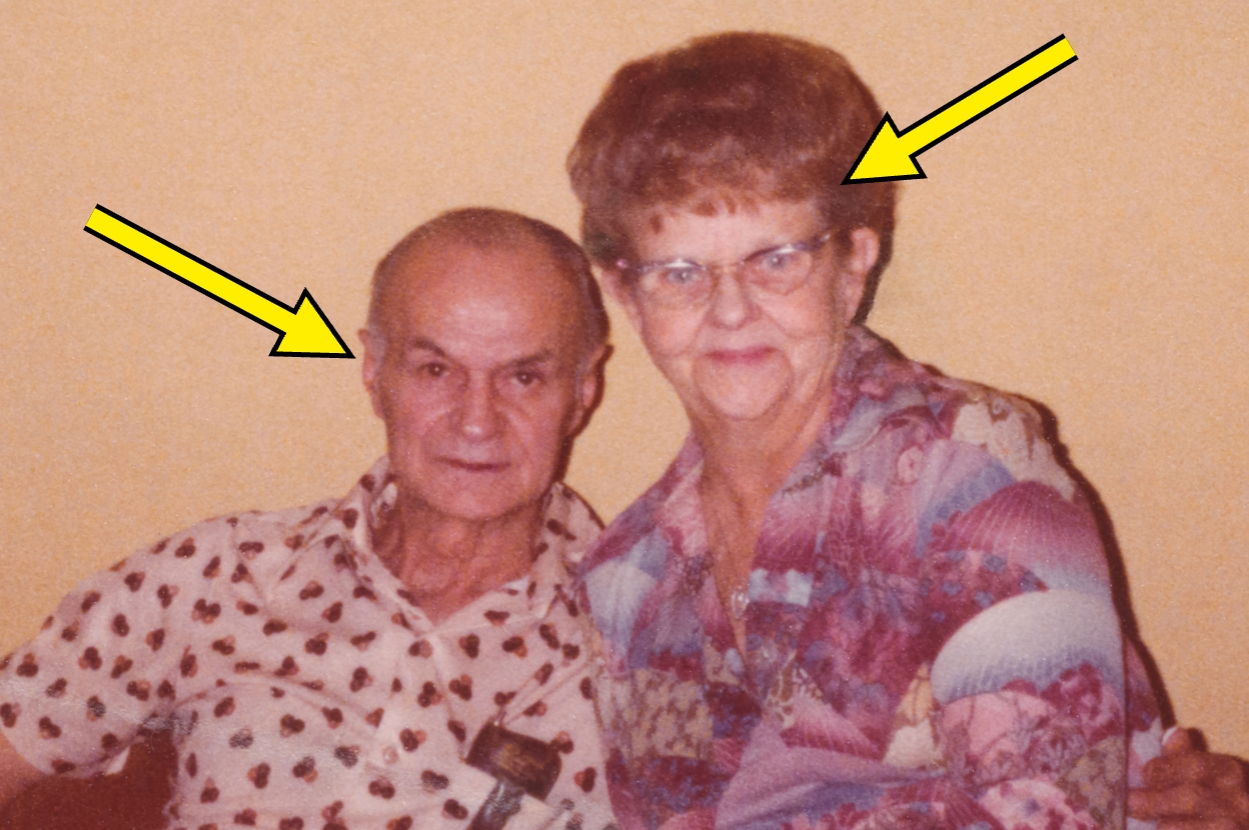 Two seniors with teased hairstyles and vintage patterned outfits pose for a casual photo, each identified by an arrow
