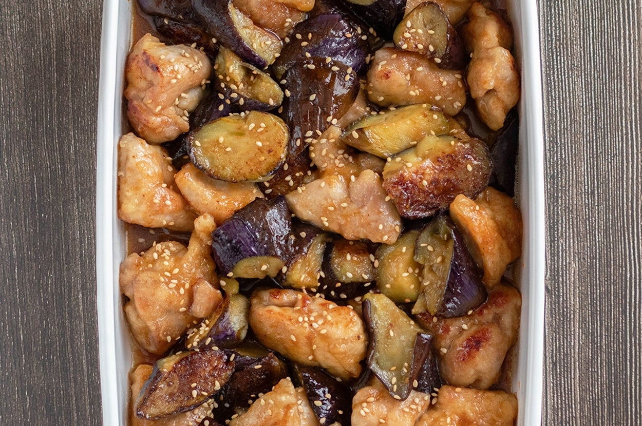 鶏肉とナスの料理が白い皿に美味しそうに盛り付けられている。ゴマがトッピングされています。