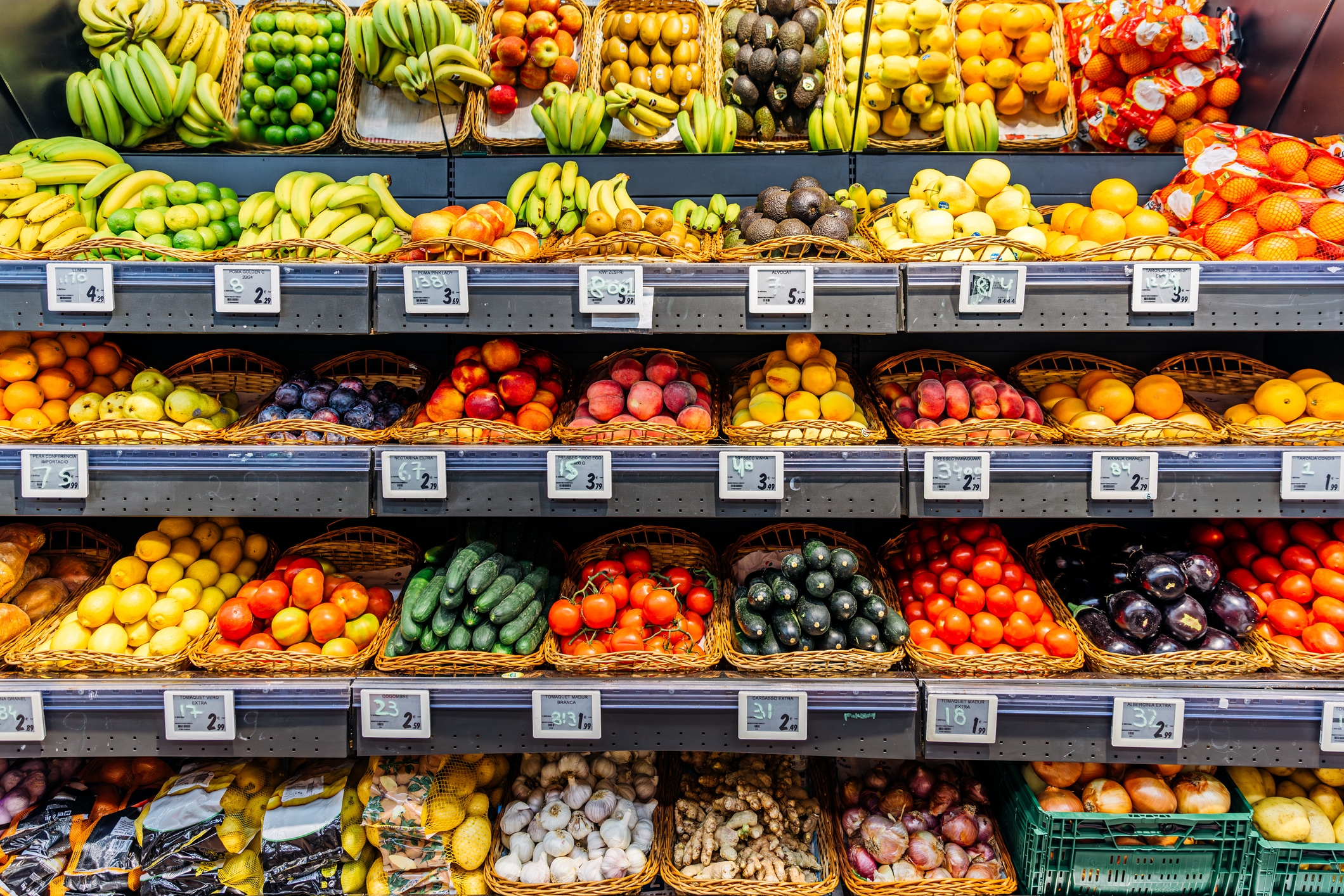Assorted fruits and vegetables displayed in baskets on grocery store shelves