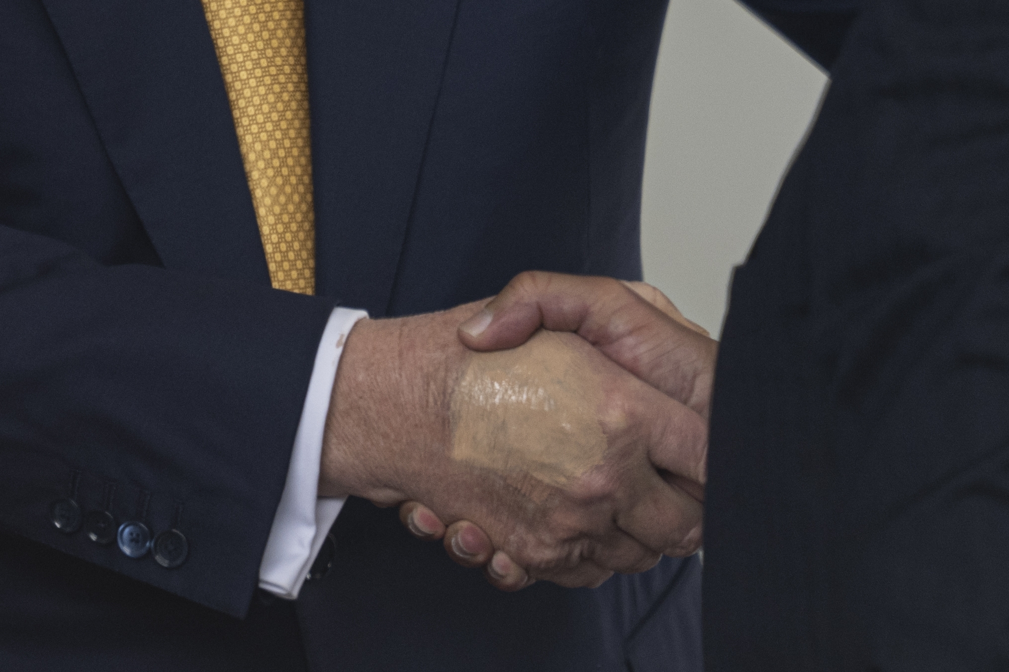 Two people in business suits shaking hands, focusing on their joined hands in a professional setting