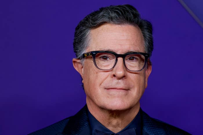 I don’t know who this is, but the image shows a person in glasses and a suit jacket posing against a plain backdrop