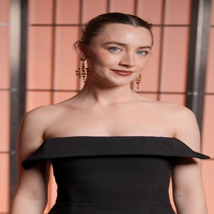 Person wearing an off-shoulder, elegant dress with striking earrings, posing at an event
