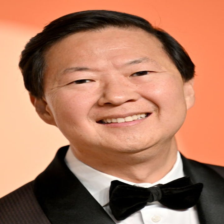 Person in a tuxedo smiling on a red carpet