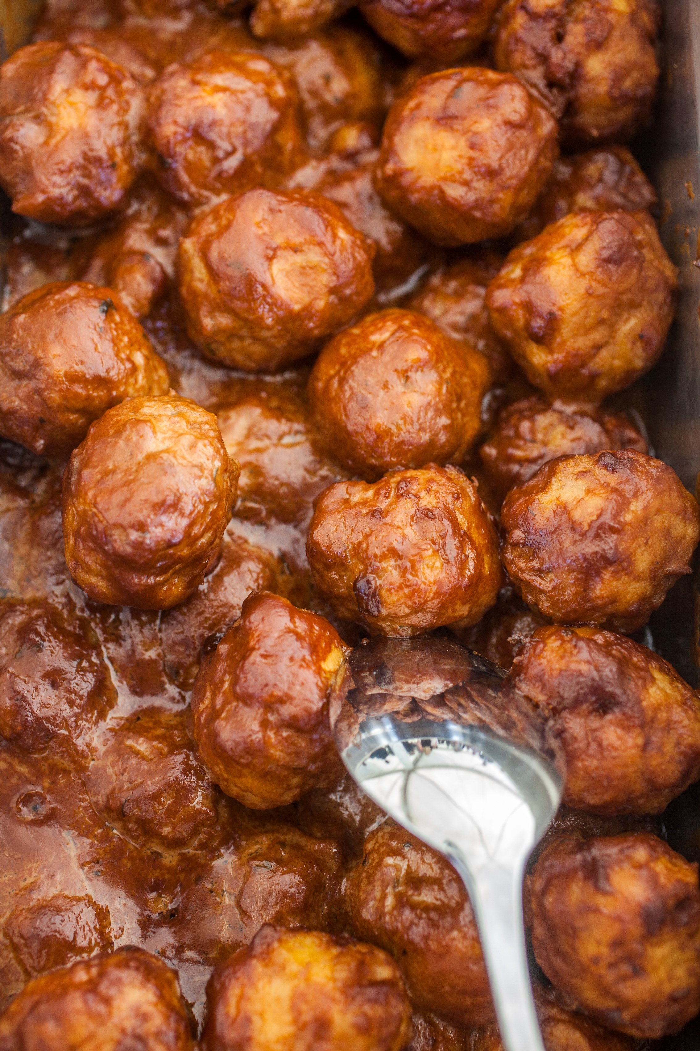 Meatballs in sauce with a spoon, suggesting a freshly cooked dish ready to serve