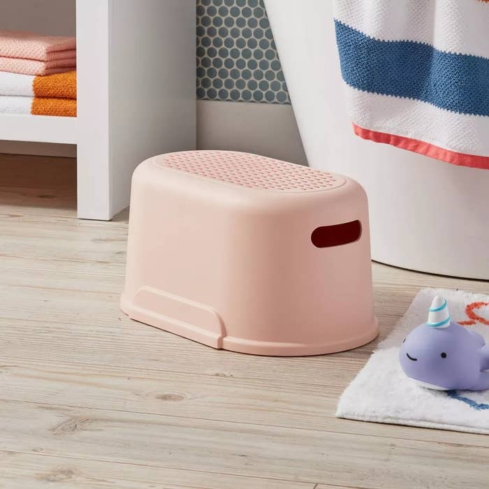 Small measurement stool adjacent to a tub, with a cute whale-shaped artifact connected a bath mat, successful a bath setting