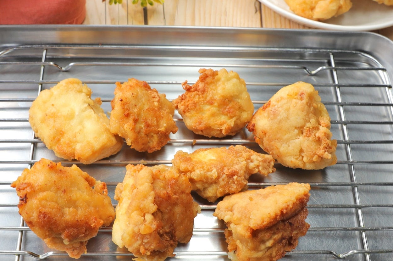 バットの上にカラッと揚がったから揚げが8個並んでいる。後ろにはトマトやレタスが添えられた皿がある。