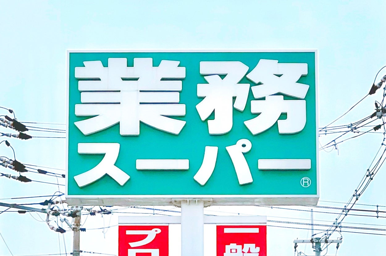 業務スーパーの看板が電線の背景に立つ。