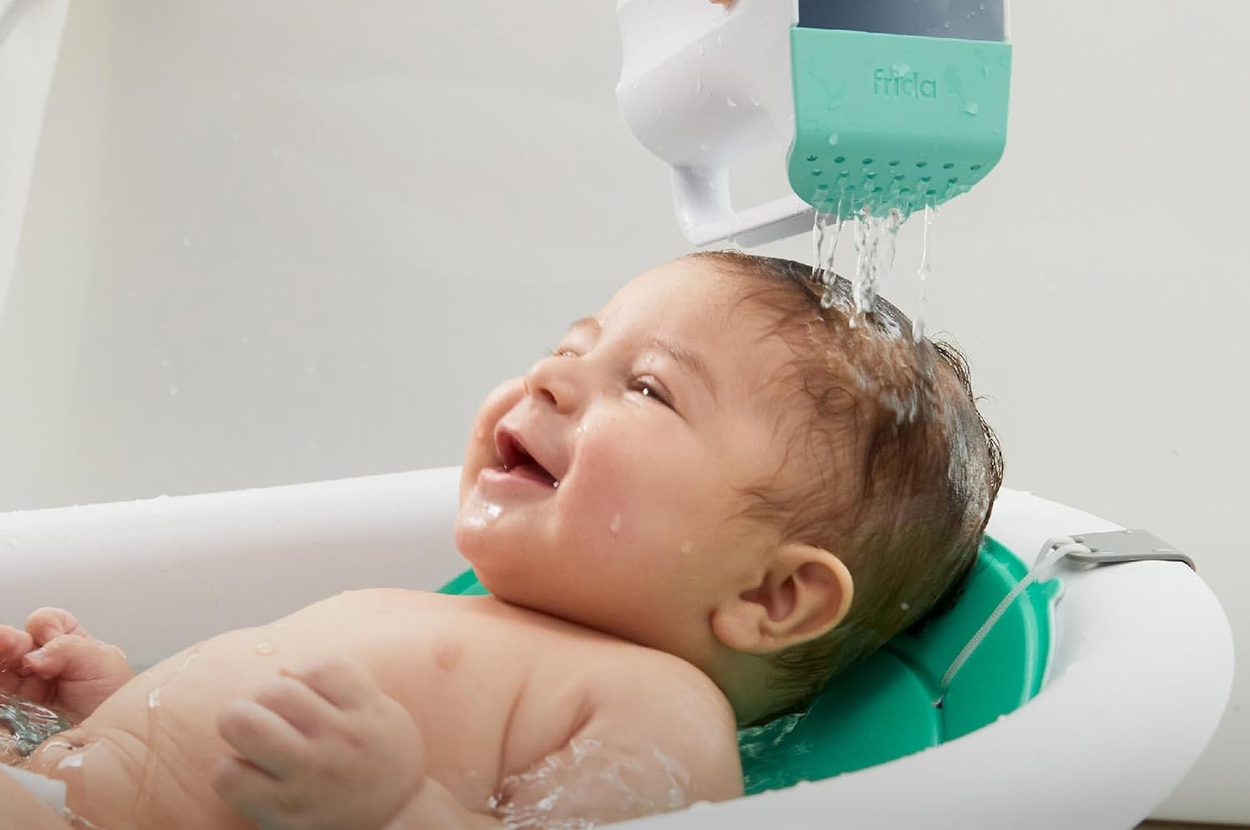 Baby in a bathtub enjoying water being poured gently over head with a specialized rinsing cup. Text: "Tear-free rinsing without a splash."