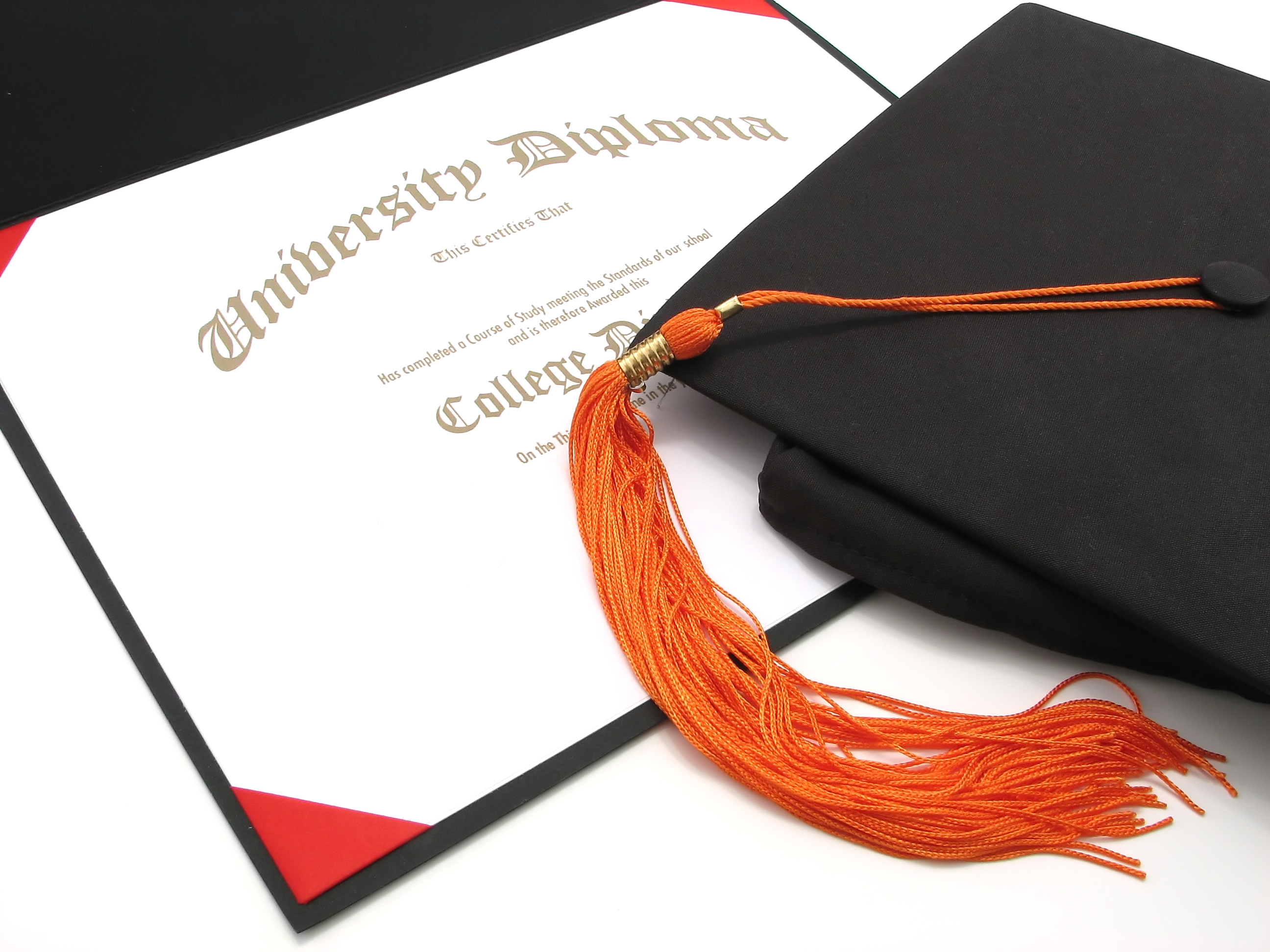 A university diploma and a graduation cap with an orange tassel are placed side by side