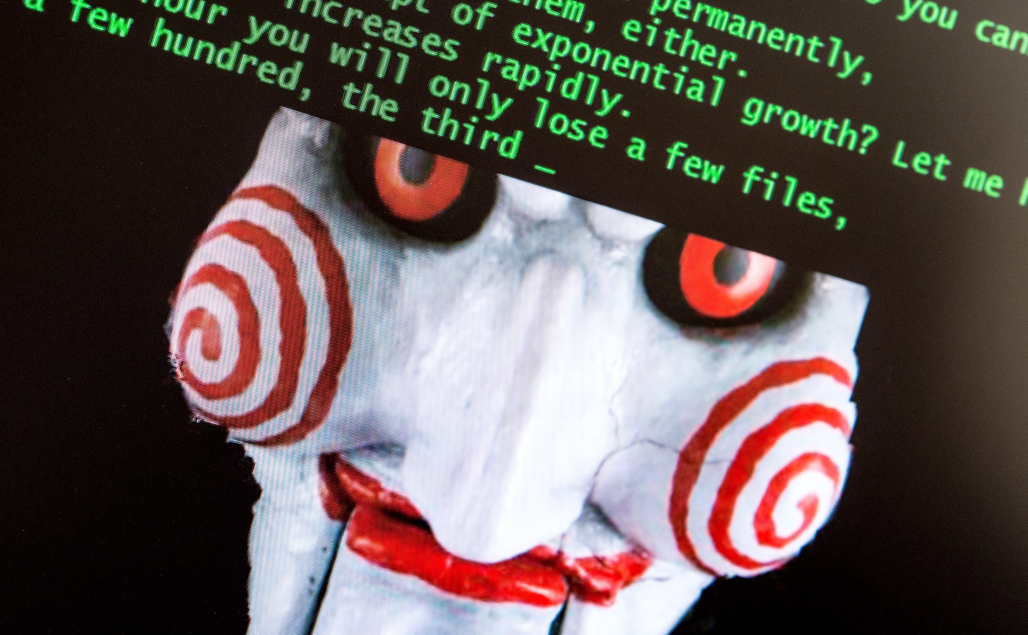A digital image of a puppet face with spirals on cheeks is on a screen displaying green command line text above it