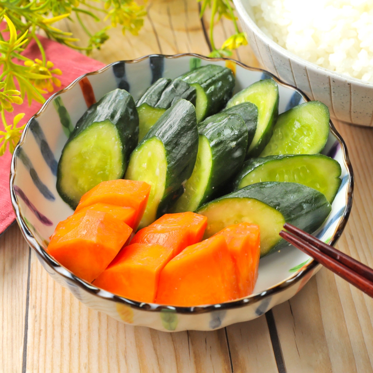 お皿に盛られたスライスされたきゅうりと一口サイズのカットされた柿。後ろにご飯の入った茶碗が見える。