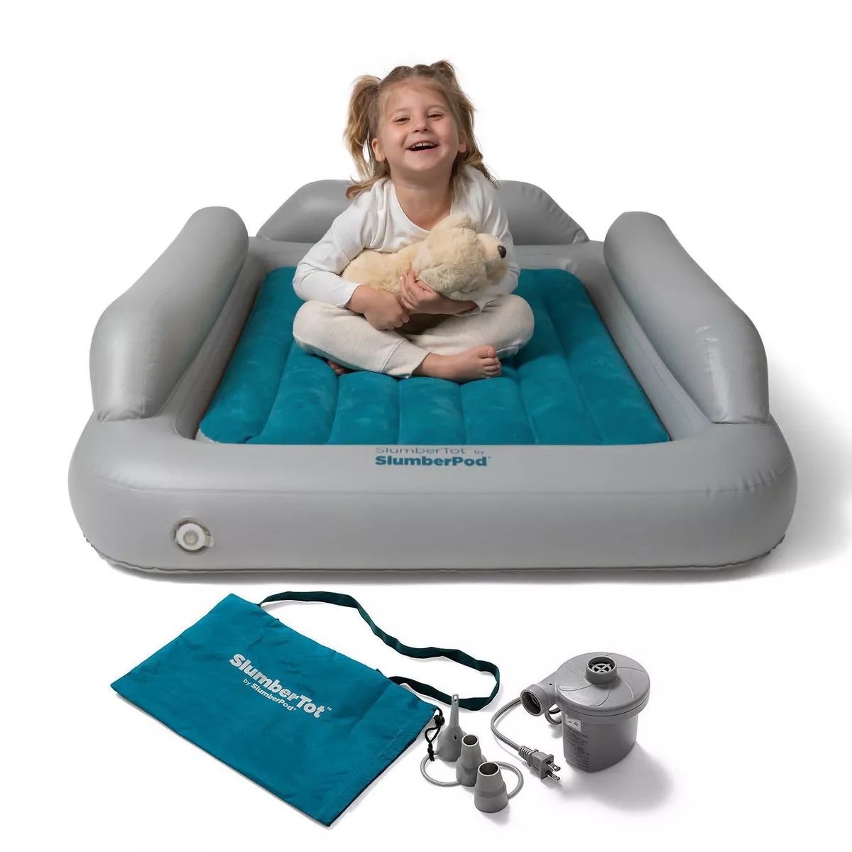 Child smiling on inflatable toddler travel bed with safety bumpers, holding a teddy bear. Includes an air pump and carry bag