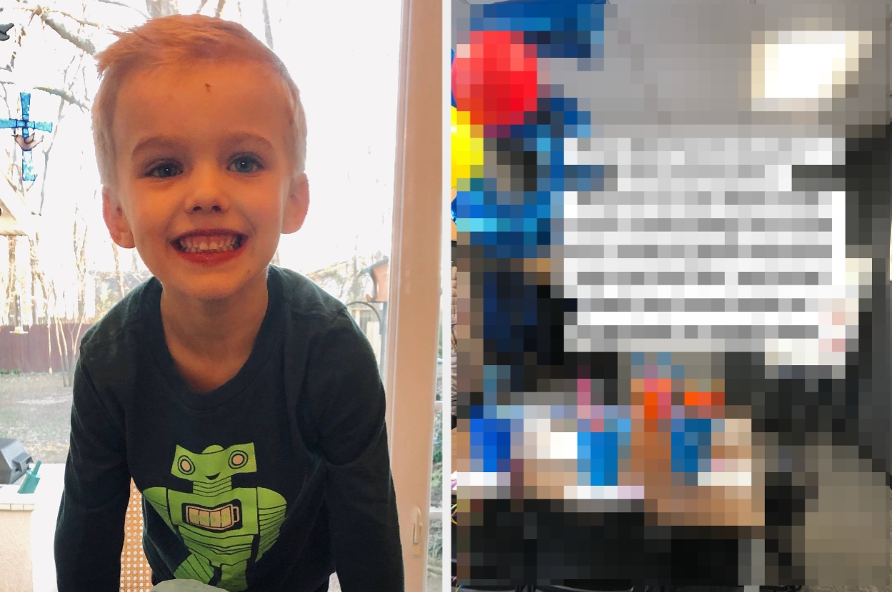 Child smiling in a robot shirt indoors; adjacent room has blurred objects and text on wall; likely a classroom or playroom setting