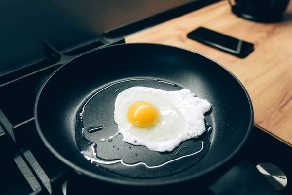 Egg frying in a black pan on a stovetop.