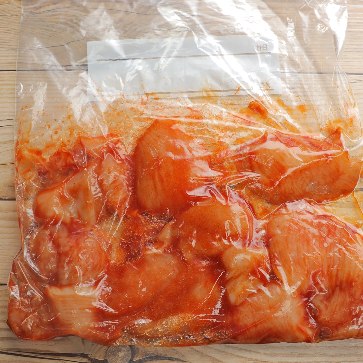 鶏肉がビニール袋に入れられ、スパイシーなソースでマリネされています。