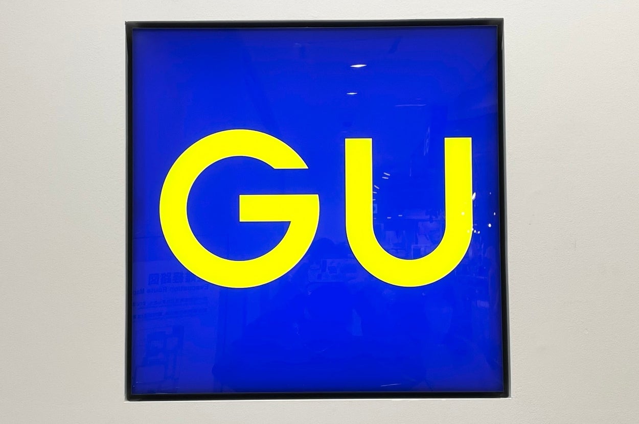 Sign displaying large "GU" letters centered against a bright background