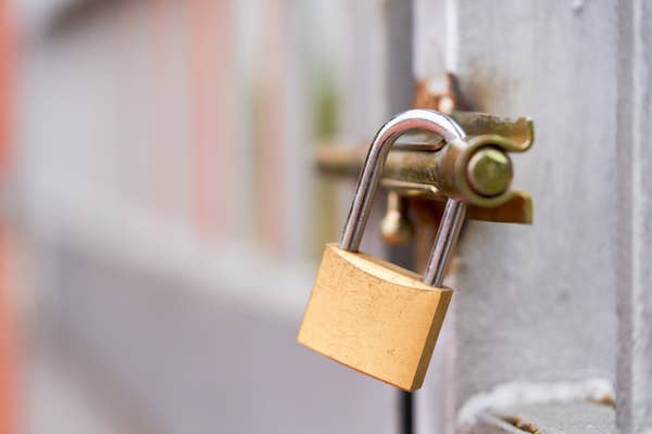 A shiny padlock secures a metal gate outdoors.