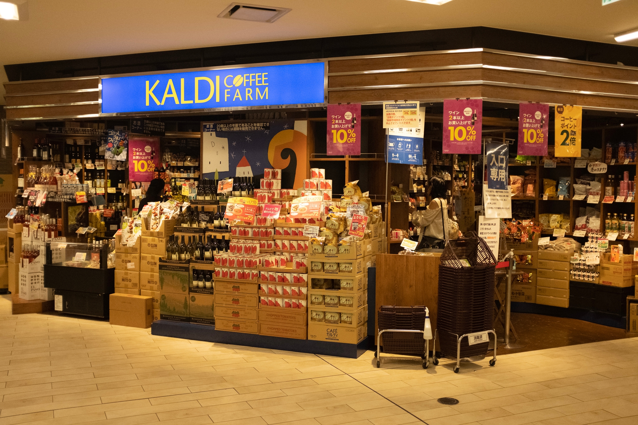 ショッピングモールにあるKALDIの店舗。店頭には多くの食品や飲料が並んでおり、特売の案内が掲示されている。