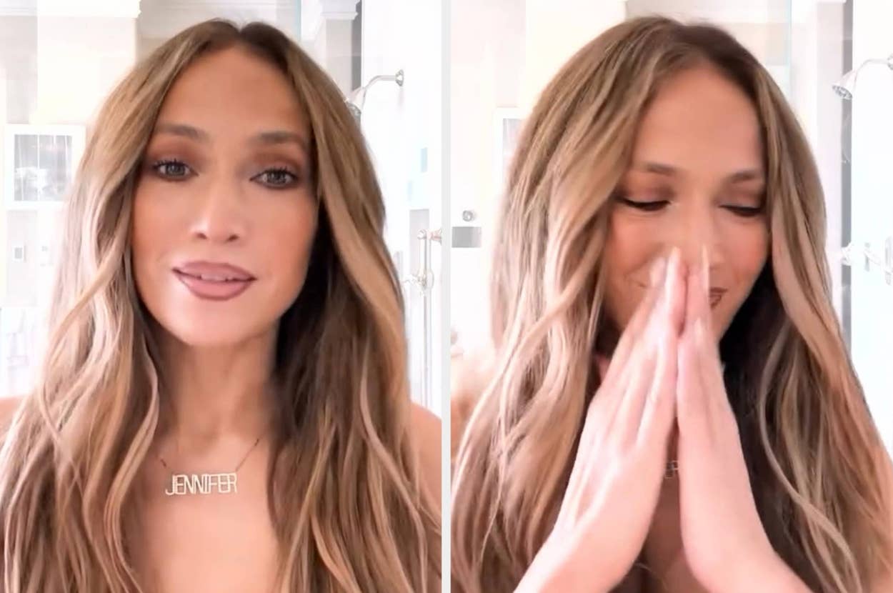 Person with long wavy hair wears a necklace with nameplate, smiling and with hands clasped in a grateful gesture
