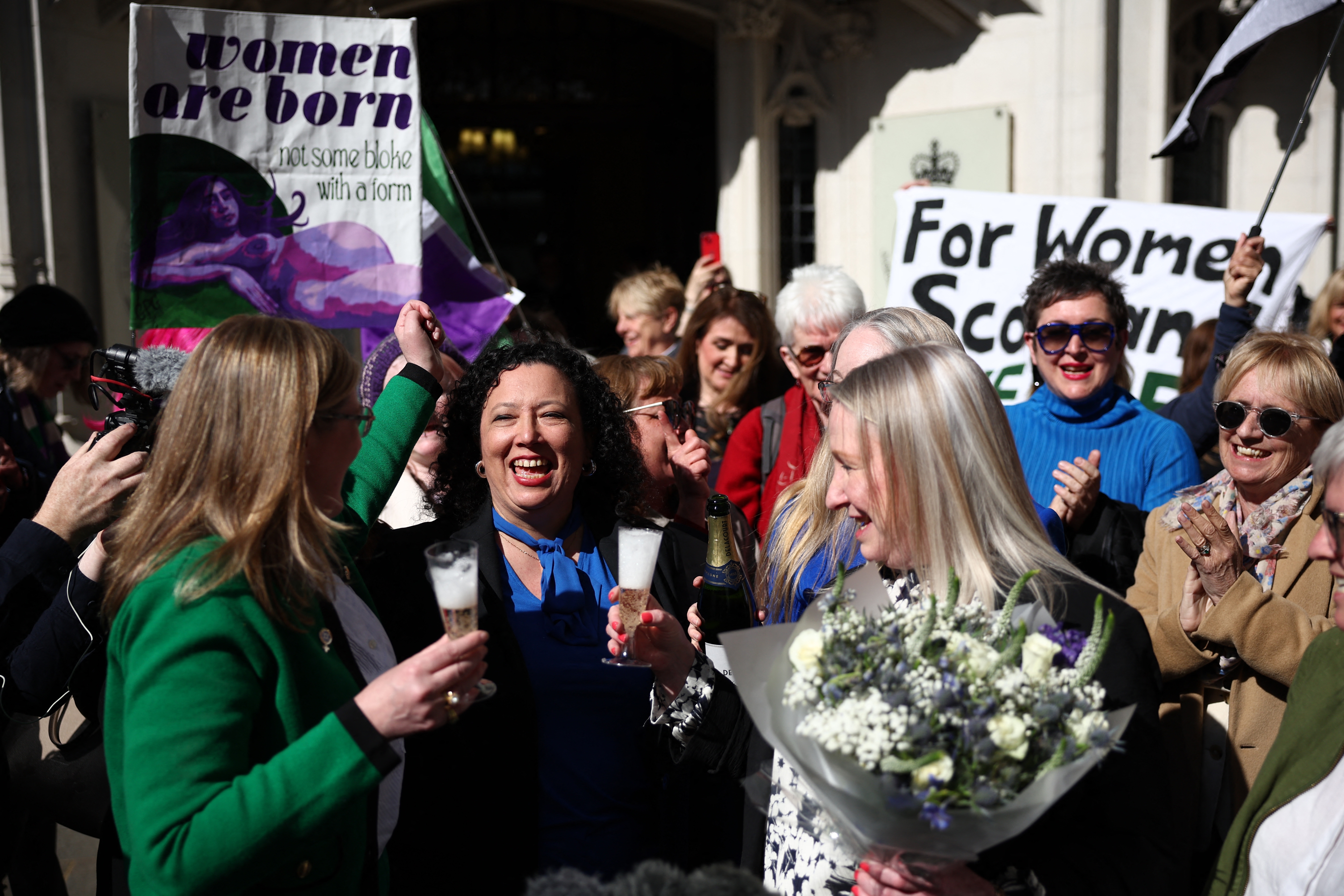 Group of women celebrating outside, holding signs advocating for women&#x27;s rights